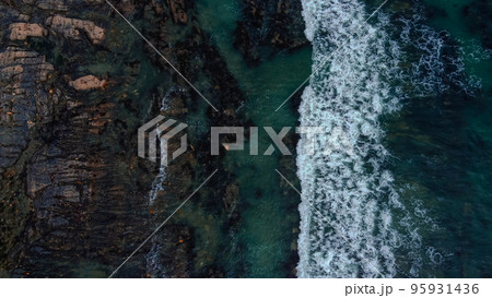 Waves break on the rocky shore of the Celtic Sea, top view. White foam on the waves. The coastline of the Atlantic. Turquoise water. Breathtaking seaside landscape. Waves break on the rocky shore of the Celtic Sea, top view. White foam on the waves. The coastline of the Atlantic. Turquoise water. Breathtaking seaside landscape. 95931436
