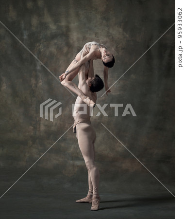 Young man and woman, ballet dancers performing isolated over dark green vintage background. Holding high 95933062