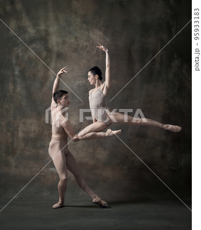 Young man and woman, ballet dancers performing isolated over dark green vintage background. Attraction of beauty Young man and woman, ballet dancers performing isolated over dark green vintage background. Attraction of beauty 95933183