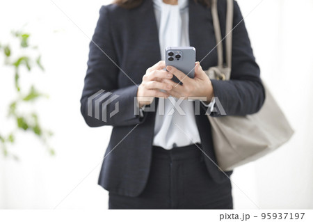 スマホを操作するビジネスウーマンの手元 95937197
