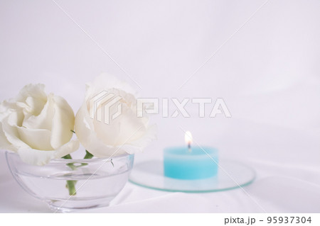 バラのような白い花とブルーのキャンドル 95937304