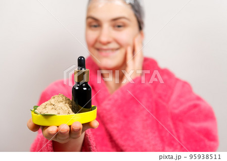A woman keeps natural cosmetics for hair care - a bottle of oils and ubtan, a scrub of herbs A woman keeps natural cosmetics for hair care - a bottle of oils and ubtan, a scrub of herbs 95938511