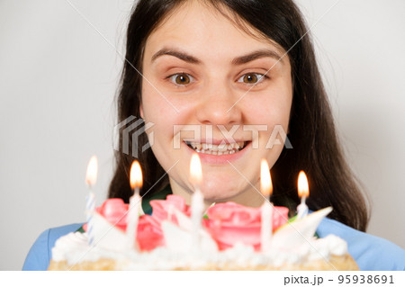 A woman doctor in a blue uniform holds a birthday cake with candles and smiles. 95938691