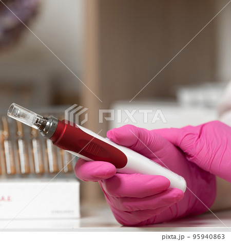 The beautician holds in his hands a dermapen, a tool for mesotherapy and cell regeneration. 95940863