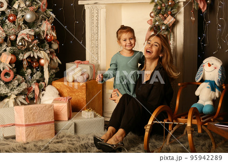 cute little blond baby girl and mom on Christmas tree and fire place background cute little blond baby girl and mom on Christmas tree and fire place background 95942289