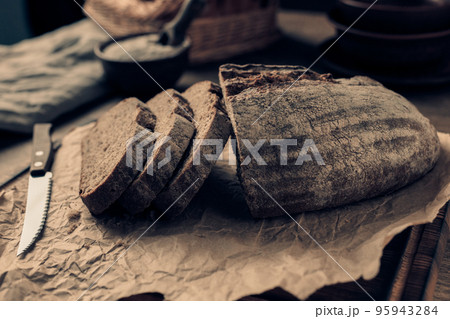 Sliced homemade bread with parchment paper at wood table. Bread on wooden tabletop 95943284