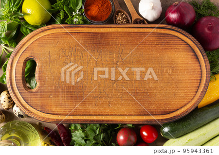 Variety of fresh vegetables and wood cutting board at table background. Cooking concept and salad 95943361