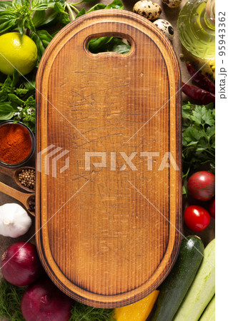 Variety of fresh vegetables and wood cutting board at table background. Cooking concept and salad 95943362
