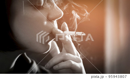 Girl is holding a cigarette in her hand, smoking closeup 95943807