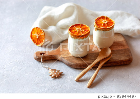 Two portions of yogurt decorated of the dry orange slices 95944497