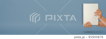 Notepad in hand. Blank notepad in the hands on a blue background. Hands hold a book without text. The girl is holding a book with an empty cover. 95944876