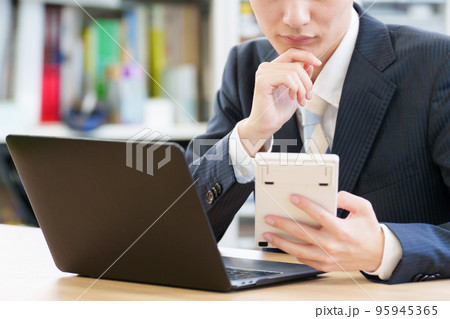 電卓を見ながら悩むビジネスマン 95945365