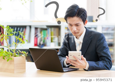 電卓を見ながら悩むビジネスマン 95945371