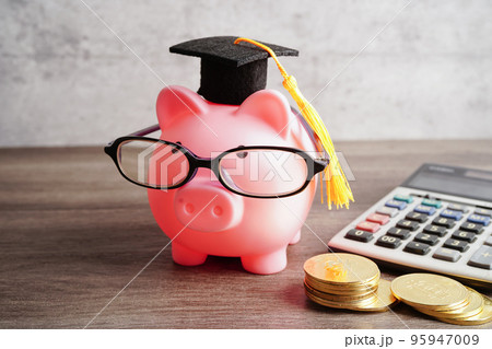 Pigging bank wearing eyeglass with coins and calculator saving bank education concept. Pigging bank wearing eyeglass with coins and calculator saving bank education concept. 95947009
