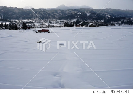 雪に覆われた山形県朝日町くぬぎ平棚田の畦道 95948341
