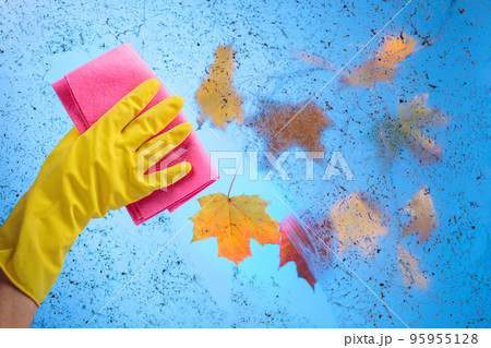 Hand in rubber glove cleaning window on a blue sky background 95955128