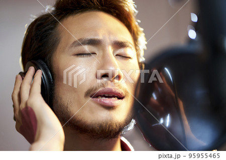 young asian adult man enjoying singing a song in modern recording studio young asian adult man enjoying singing a song in modern recording studio 95955465
