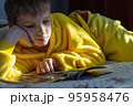 boy lying in bed with a book. child reading home education 95958476