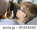 A boy with his guinea pig reading book home education 95958480