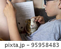 A boy with his guinea pig reading book home education 95958483