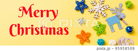 Merry Christmas text. Top view of yellow background with New Year toys and decorations. Christmas time Banner concept with copy space Merry Christmas text. Top view of yellow background with New Year toys and decorations. Christmas time Banner concept with copy space 95958509