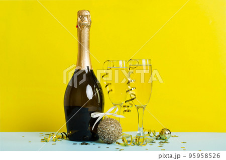 Champagne bottle with confetti, glasses and christmas decor on colored holiday background. Flat lay New Year decorations 95958526