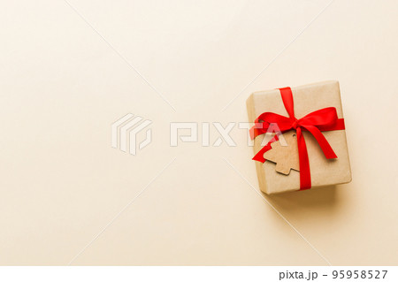 wrapped christmas or other holiday handmade present in paper with colored ribbon. Present box, decoration of gift on colourfull table, top view with copy space 95958527