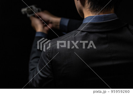 拳銃を構えるスーツ姿の人物 95959260