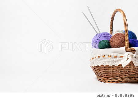 Wicker basket with colored balls of yarn for knitting or crocheting. Hobbies and recreation with needlework. On white background with place for text copy space 95959398