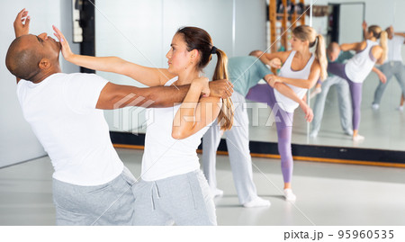 Woman and man at self protection workout, training attack movements Woman and man at self protection workout, training attack movements 95960535