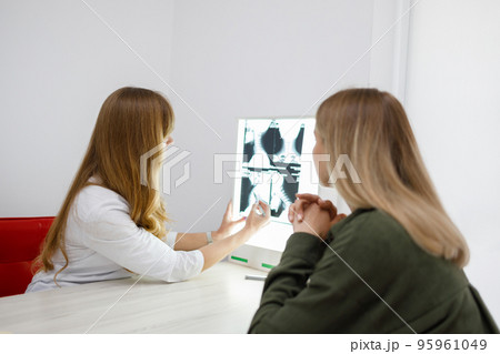 Neurologist showing neck scan to young woman in clinic 95961049