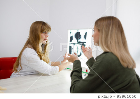 Young female patient and her neurologist doctor are discussing the results of a tomographic scan of the neck 95961050