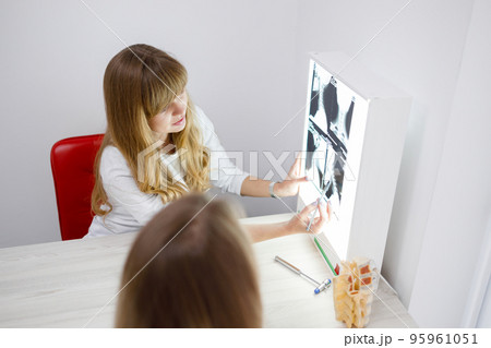 Neurologist considers and discusses with female patient an x-ray tomography image of neck 95961051
