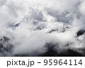 A landscape of the Dolomites Mountain Range covered in the fog under a cloudy sky in Italy 95964114