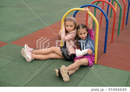 A child with a cast on his arm is playing with a friend on the playground in the yard. Life and health insurance A child with a cast on his arm is playing with a friend on the playground in the yard. Life and health insurance 95966686