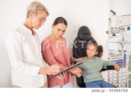 Mother and child consulting an eye doctor with a clipboard after an eye test or exam for healthy vision. Family, optometrist or optician helping a mom and kid with eyesight advice or eye care results 95966708