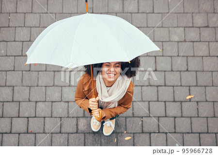 Happy, relax and girl with rain umbrella enjoying outdoor, urban and winter weather with excited smile. Happiness, peace and wellness of black woman with afro standing in rainy city top view. 95966728