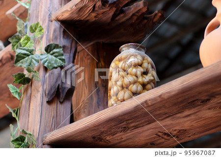 pickled garlic in a large glass jar on a wooden shelf. Tasty pickled garlic pickled garlic in a large glass jar on a wooden shelf. Tasty pickled garlic 95967087