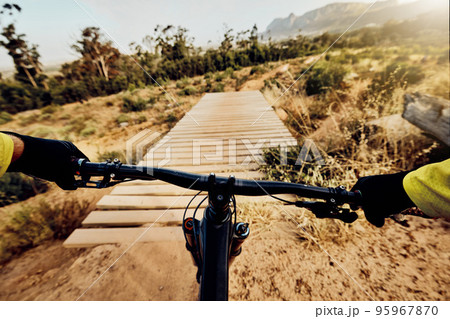 POV perspective, mountain bike and man cycling on hill, bridge and path for adventure, speed and sports challenge, action and off road race in nature. Bicycle handle, athlete and outdoor competition 95967870