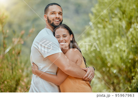 Black couple, hug and smile in woods together, outdoor and bush with love, romance or bonding on vacation in nature. Happy, man and woman embrace in portrait, forest or trees for happiness 95967963