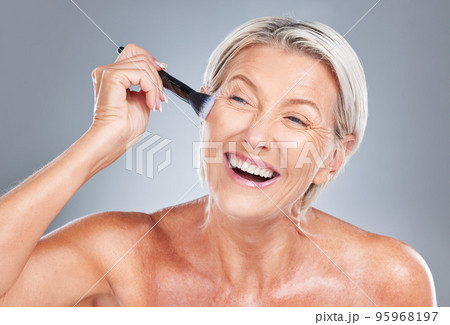 Happy, senior woman and makeup brush in studio for beauty, skincare and wrinkles treatment on a grey background. Face, cheek and product by elderly model happy, excited and smiling about cosmetics 95968197