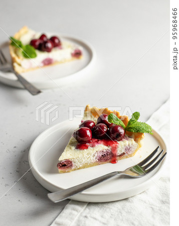 Portion of cottage cheese casserole or pudding with cherry and mint leaveson white background. Cherry cheesecake 95968466