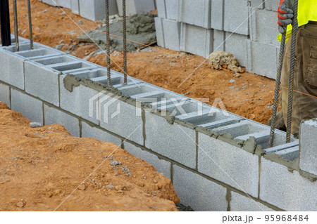 Mason bricklayer worker is laying mounting wall of aerated concrete blocks for building Mason bricklayer worker is laying mounting wall of aerated concrete blocks for building 95968484