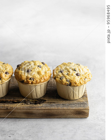 Chocolate chip muffins on wooden board on light gray background with text space Chocolate chip muffins on wooden board on light gray background with text space 95968495