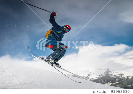 male skier jumping from mountain creating snow plume, winter extreme sport, downhill skiing 95968650