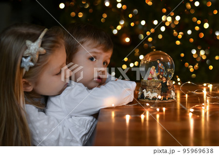Children looking at a glass ball with a scene of the birth of Jesus Christ 95969638