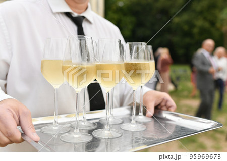 A waiter serving champagne at a wedding A waiter serving champagne at a wedding 95969673