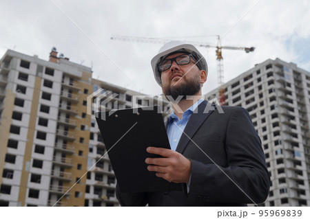 Bearded building inspector making notes at construction site 95969839