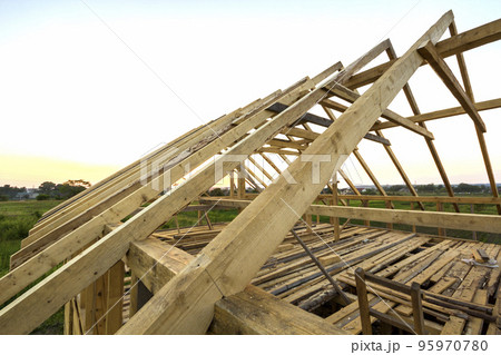 New wooden house under construction. Close-up of attic roof frame against clear sky from inside. Ecological dream home of natural materials. Building, construction and renovation concept. 95970780
