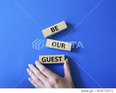 Be our guest symbol. Concept word Be our guest on wooden blocks. Beautiful blue background. Businessman hand. Business and Be our guest concept. Copy space 95972071